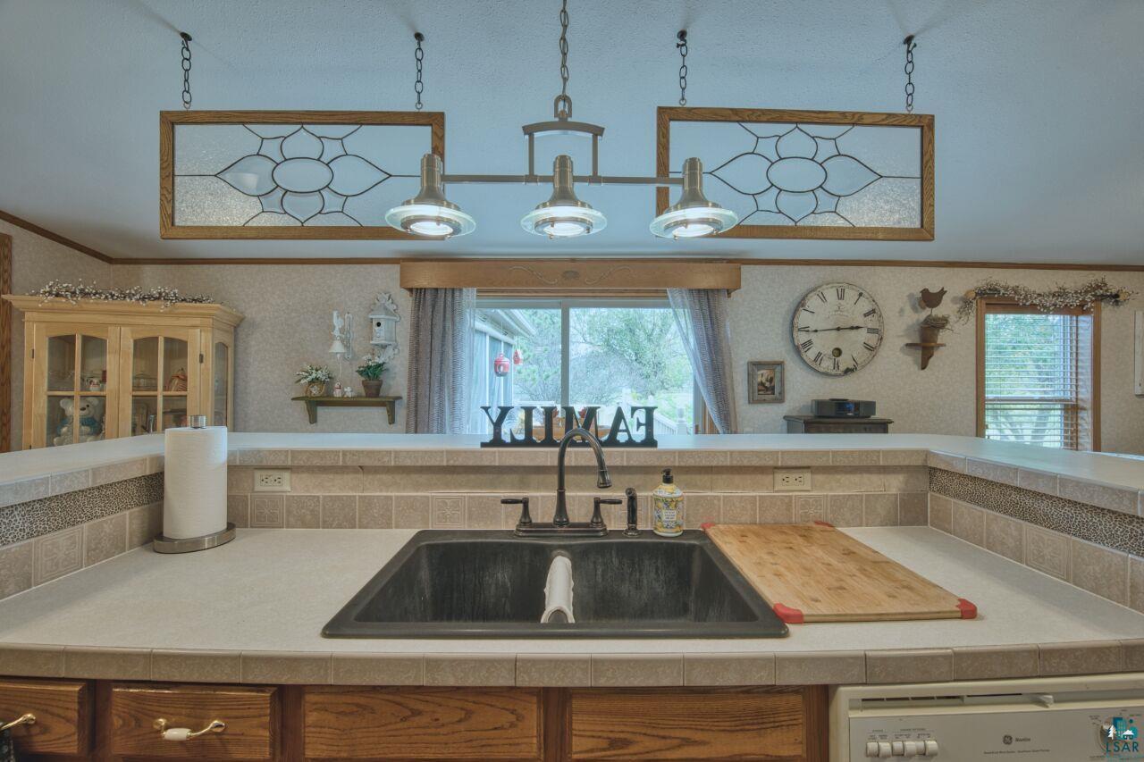 3360 North Leighton Road Hibbing, MN 55746 - Photo 12 of 60 Kitchen featuring light countertops, dishwasher, wallpapered walls, ornamental molding, and decorative backsplash