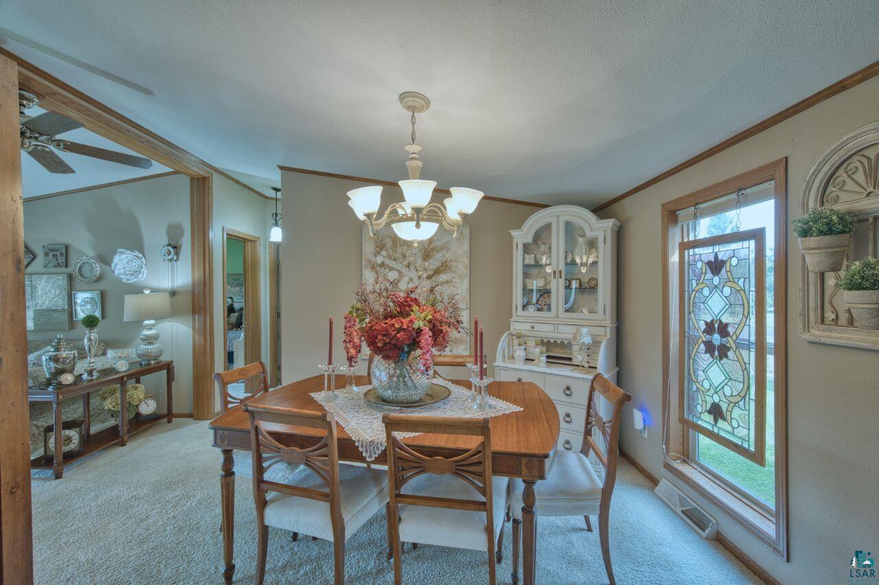 3360 North Leighton Road Hibbing, MN 55746 - Photo 15 of 60 Dining room with ornamental molding, light colored carpet, and a chandelier