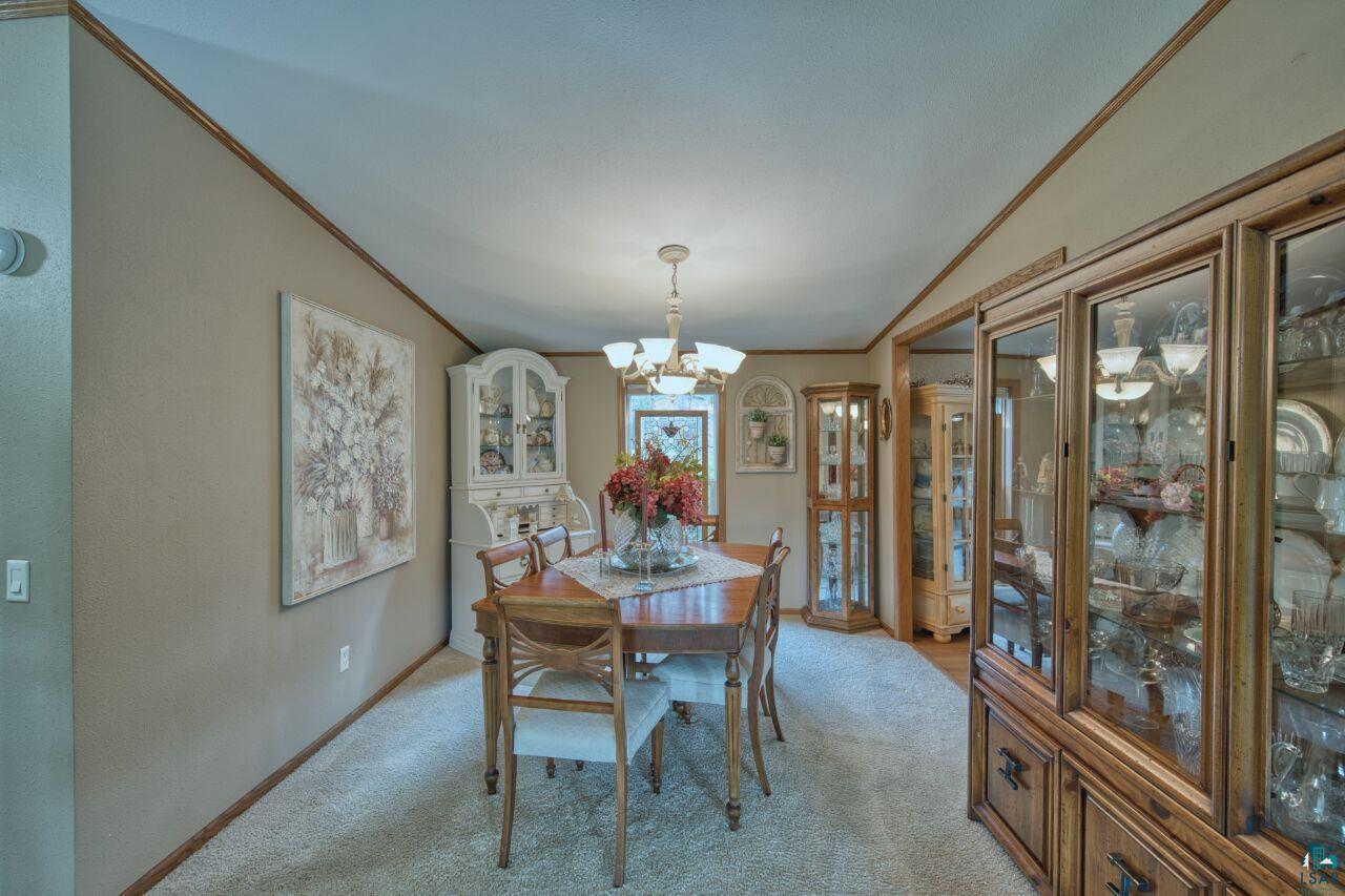 3360 North Leighton Road Hibbing, MN 55746 - Photo 16 of 60 Dining area with ornamental molding, a chandelier, light colored carpet, and vaulted ceiling