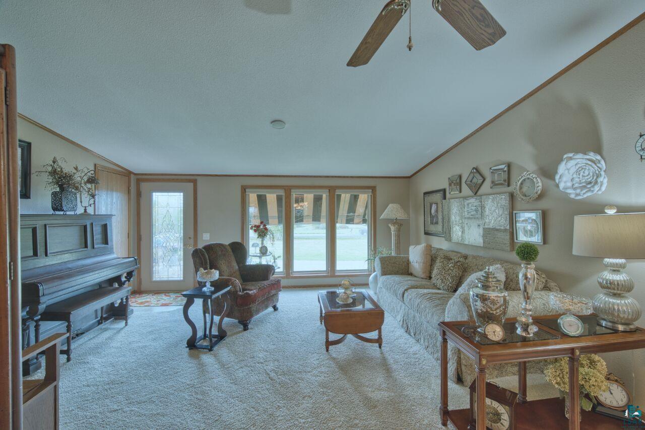 3360 North Leighton Road Hibbing, MN 55746 - Photo 17 of 60 Carpeted living area with healthy amount of natural light, ornamental molding, vaulted ceiling, and a textured ceiling