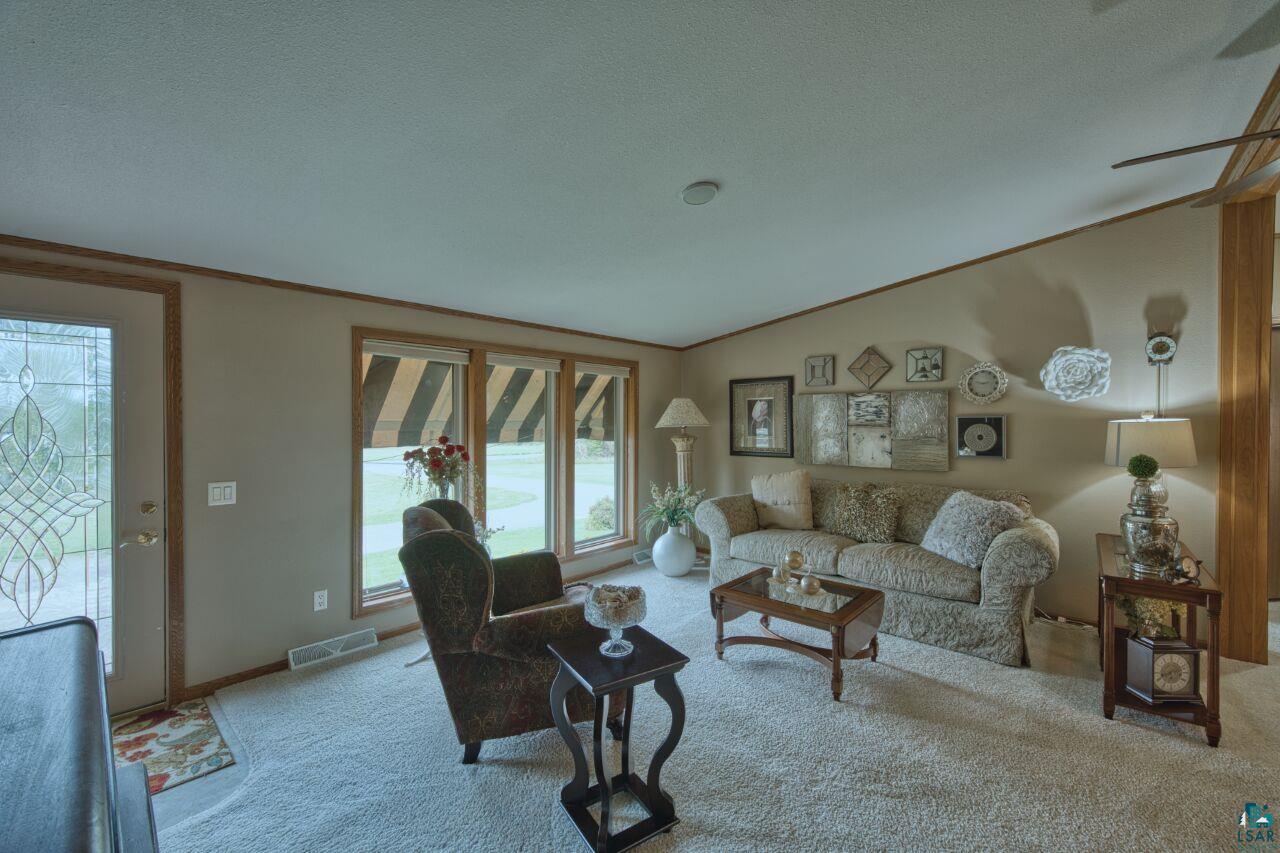 3360 North Leighton Road Hibbing, MN 55746 - Photo 19 of 60 Carpeted living room featuring ornamental molding, a textured ceiling, and vaulted ceiling