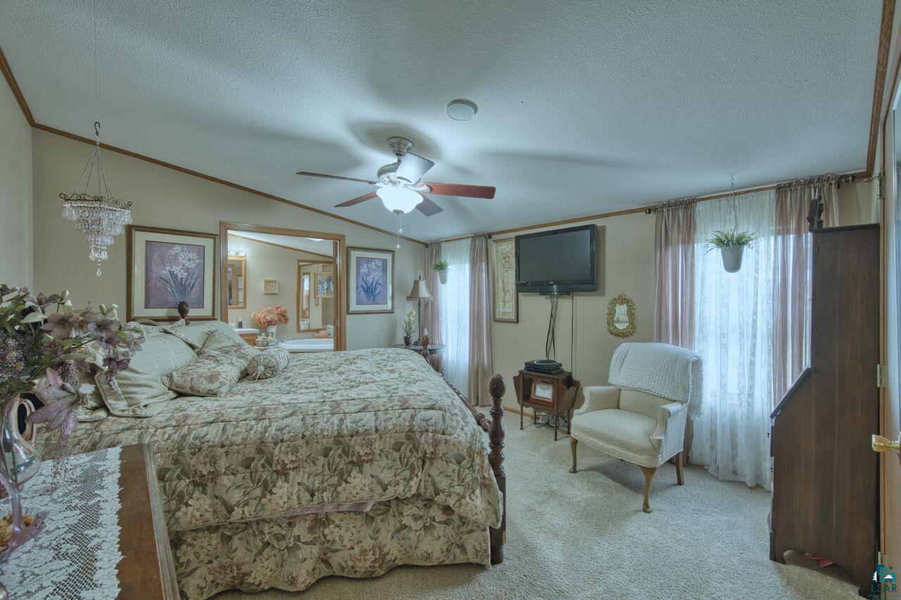 3360 North Leighton Road Hibbing, MN 55746 - Photo 20 of 60 Bedroom featuring carpet flooring, crown molding, multiple windows, a textured ceiling, and a ceiling fan