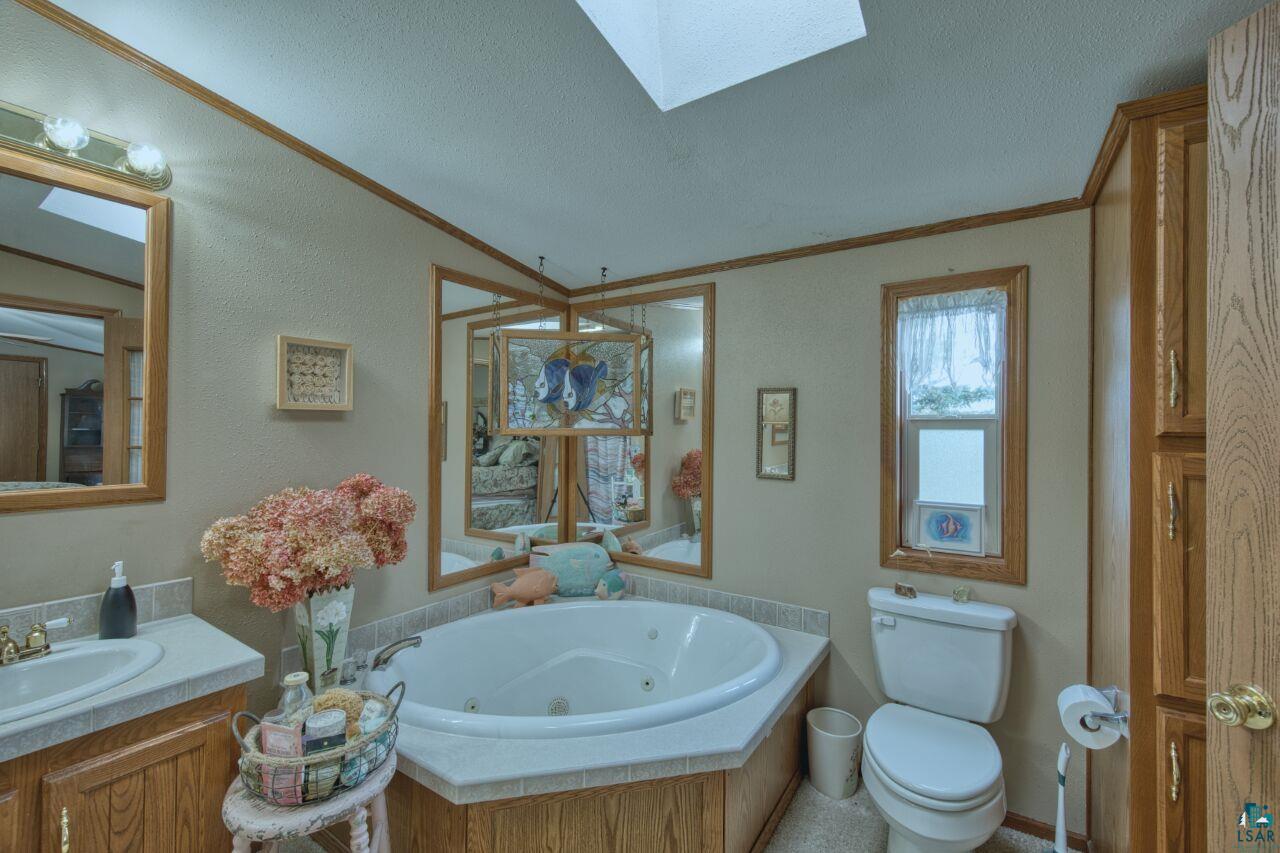 3360 North Leighton Road Hibbing, MN 55746 - Photo 23 of 60 Full bath with a jetted tub, vanity, a skylight, crown molding, and a textured ceiling