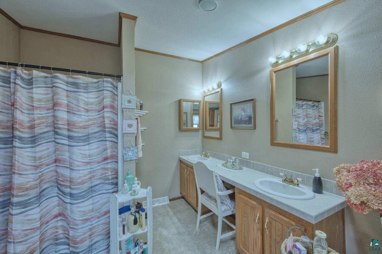 3360 North Leighton Road Hibbing, MN 55746 - Photo 24 of 60 Full bathroom with double vanity, crown molding, and a shower with shower curtain
