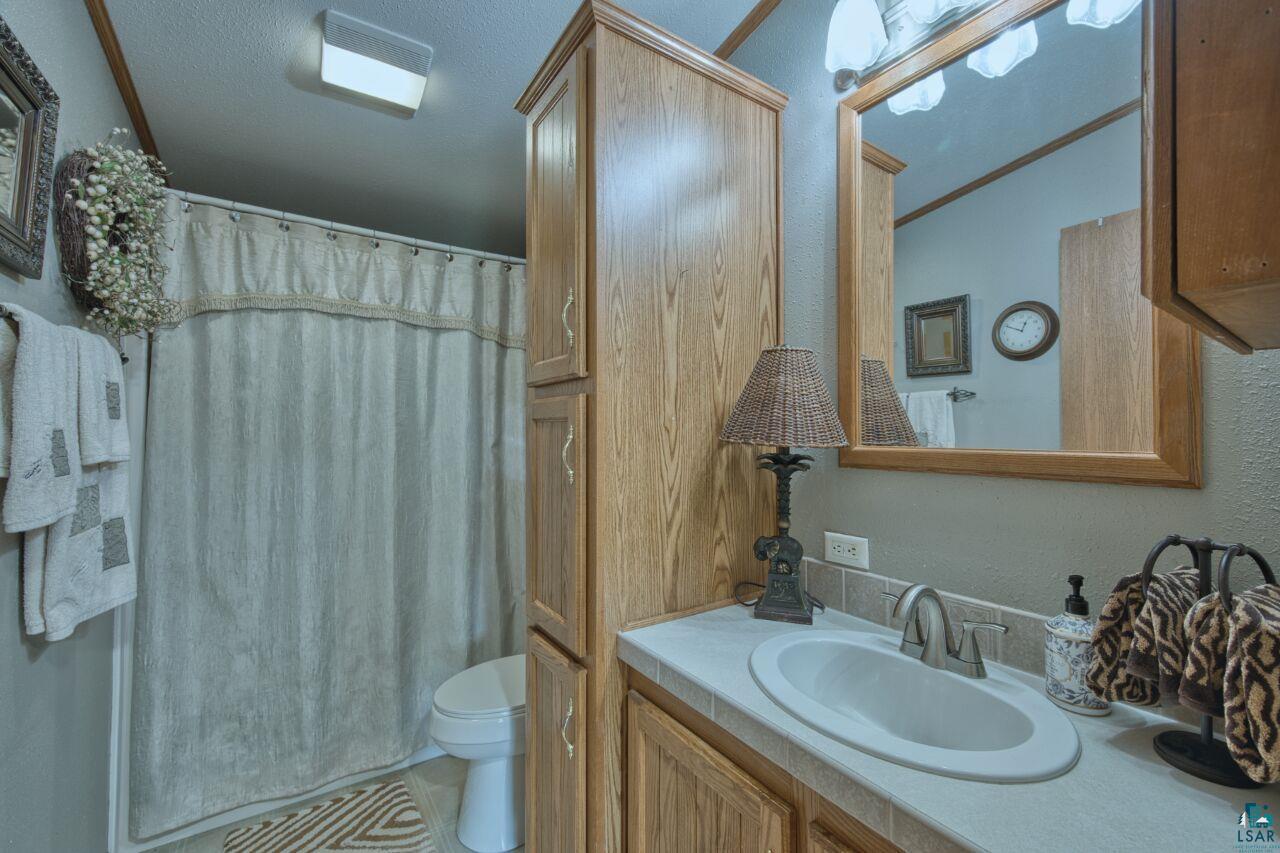 3360 North Leighton Road Hibbing, MN 55746 - Photo 29 of 60 Full bath featuring vanity, a textured wall, curtained shower, and tile patterned flooring