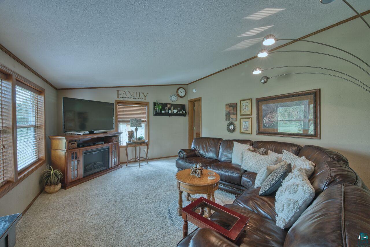 3360 North Leighton Road Hibbing, MN 55746 - Photo 5 of 60 Living room featuring vaulted ceiling, carpet, healthy amount of natural light, a textured ceiling, and ornamental molding
