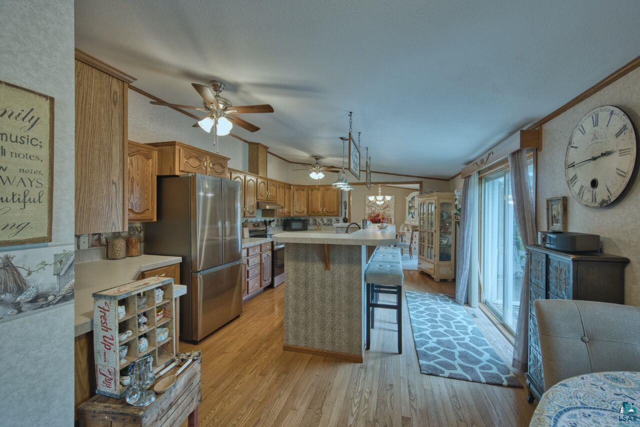 3360 North Leighton Road Hibbing, MN 55746 - Photo 7 of 60 Kitchen featuring vaulted ceiling, a breakfast bar, light countertops, light wood-type flooring, and appliances with stainless steel finishes