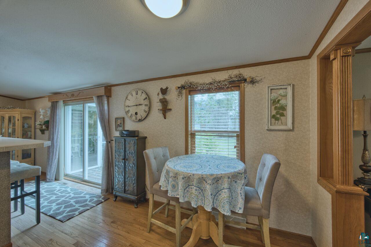 3360 North Leighton Road Hibbing, MN 55746 - Photo 8 of 60 Dining room with crown molding, wood finished floors, wallpapered walls, and a textured ceiling