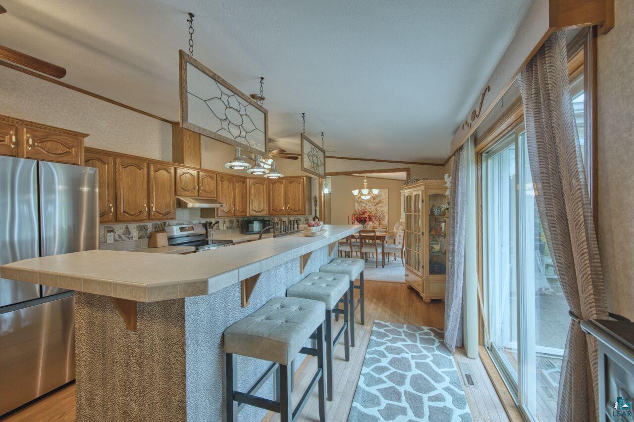 3360 North Leighton Road Hibbing, MN 55746 - Photo 9 of 60 Kitchen featuring light wood finished floors, a breakfast bar area, light countertops, appliances with stainless steel finishes, and lofted ceiling