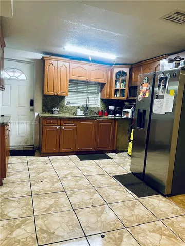 a kitchen with stainless steel appliances kitchen island granite countertop a refrigerator and a stove top oven