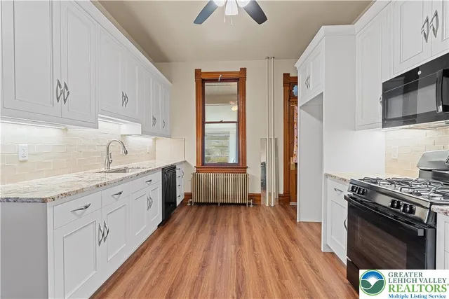 a kitchen with granite countertop a sink cabinets and wooden floor