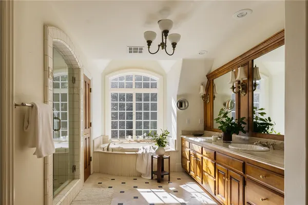 a bathroom with a sink a large mirror and a bathtub next to a window