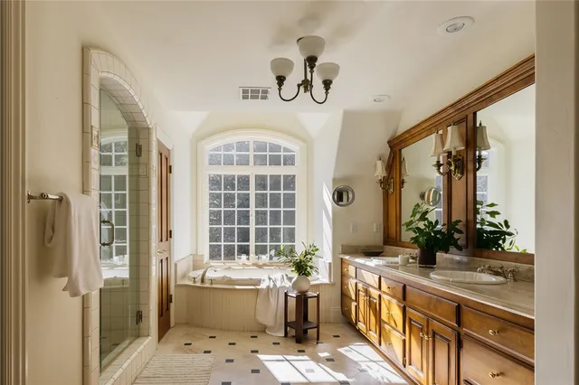 a bathroom with a sink a large mirror and a bathtub next to a window
