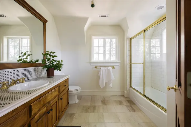 a bathroom with a granite countertop sink a toilet and shower