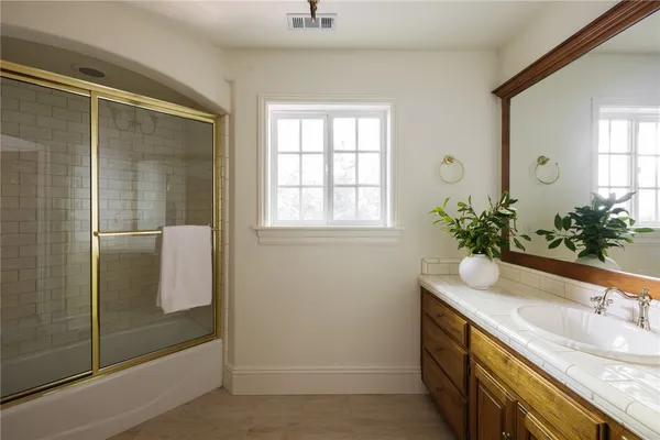 a bathroom with a granite countertop sink a mirror and a shower