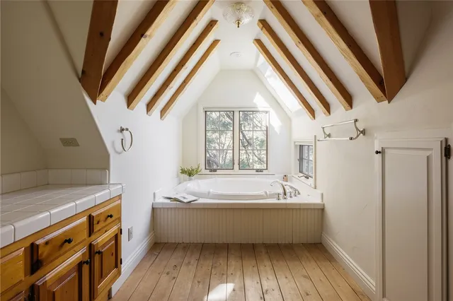 a bathroom with a bathtub a sink and wooden floor
