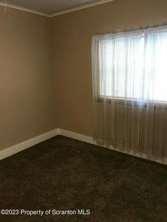 an empty room with wooden floor and windows with curtains