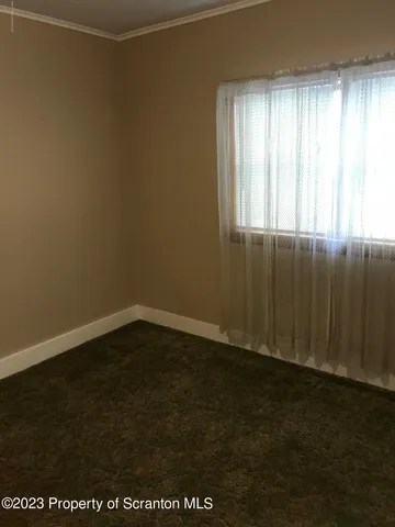 an empty room with wooden floor and windows with curtains