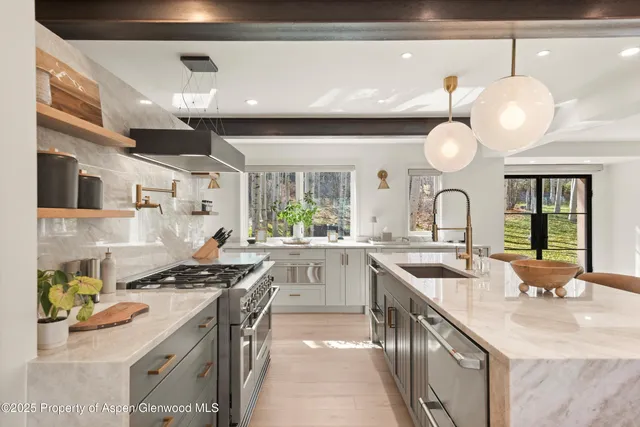 a kitchen with stainless steel appliances a sink a stove and a wooden floors
