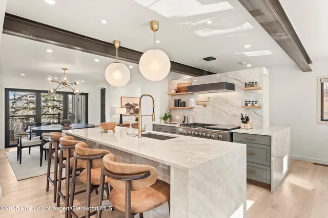 a kitchen with stainless steel appliances a stove a table and chairs in it