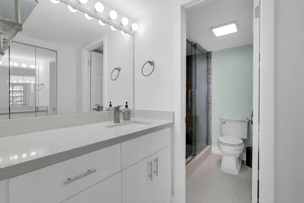 a bathroom with a sink a toilet a large mirror and shower