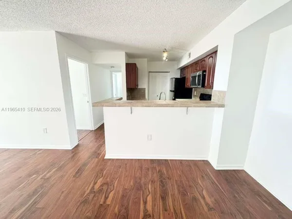 a view of kitchen with stainless steel appliances wooden floor and chair