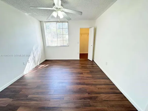 an empty room with wooden floor chandelier fan and windows