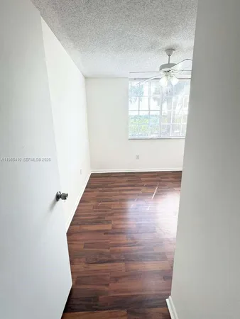 an empty room with wooden floor cabinet and windows