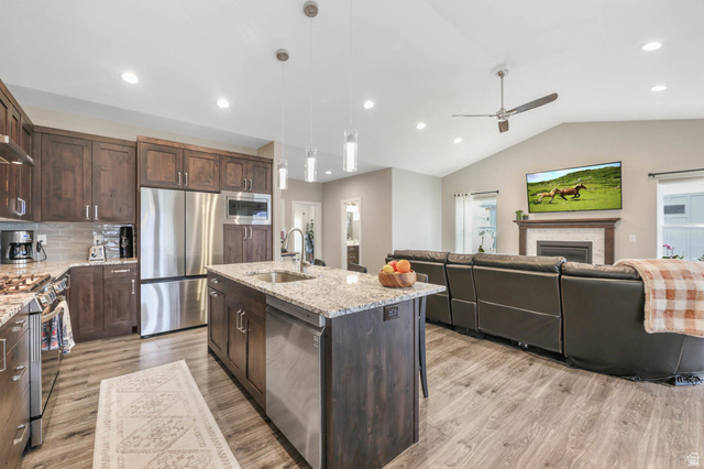 4527 North Seven Bridges Road Eden, UT 84310 - Photo 62 of 65 Kitchen featuring light stone counters, stainless steel appliances, open floor plan, a kitchen island with sink, and light wood-style flooring