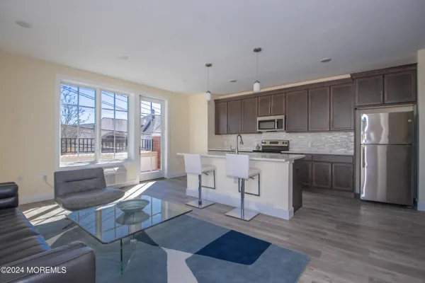 a kitchen with stainless steel appliances granite countertop a stove a refrigerator a sink a dining table and chairs with wooden floor