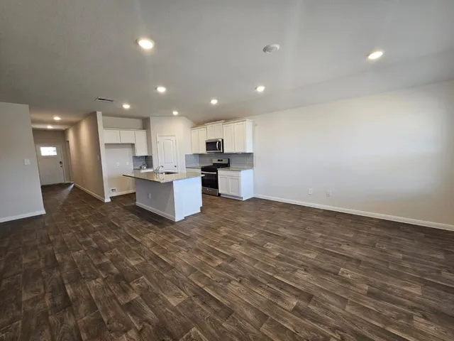 a view of kitchen with kitchen island wooden floor center island and stainless steel appliances