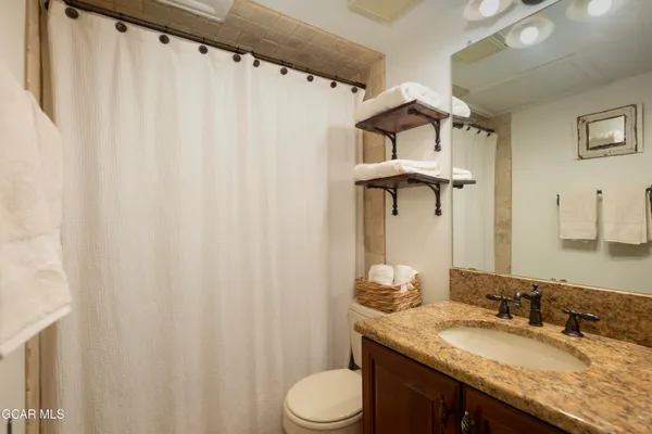 a bathroom with a granite countertop sink vanity mirror and toilet