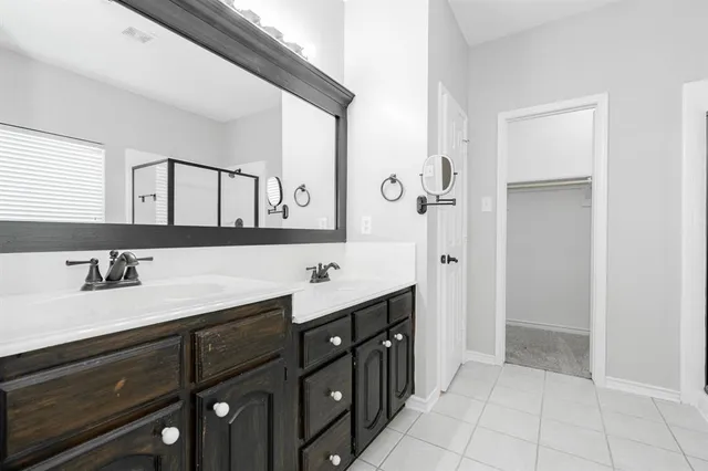 a bathroom with a double vanity sink a mirror and a bathtub