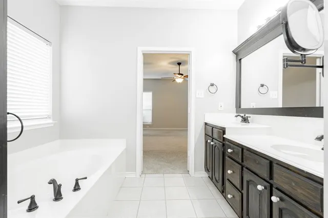 a bathroom with a tub sink and mirror
