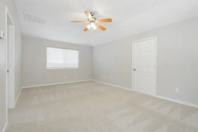 an empty room with a window and a ceiling fan