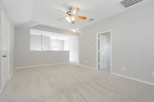 an empty room with chandelier fan and windows
