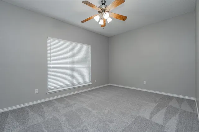 an empty room with chandelier fan and windows