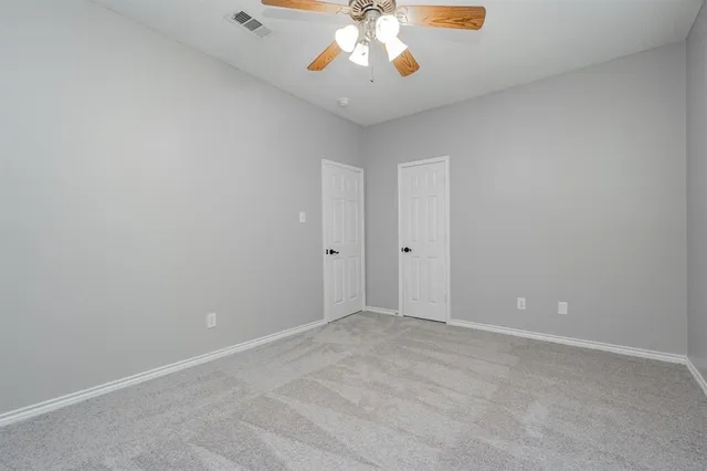 an empty room with a chandelier fan and wooden floor