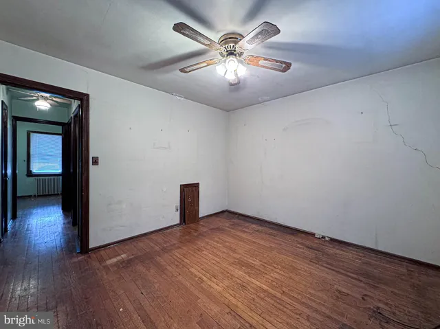 an empty room with wooden floor and a ceiling fan