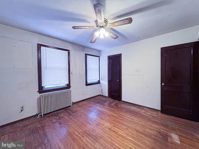 a view of an empty room with wooden floor and windows