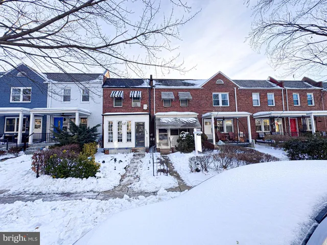 a front view of a building with large trees