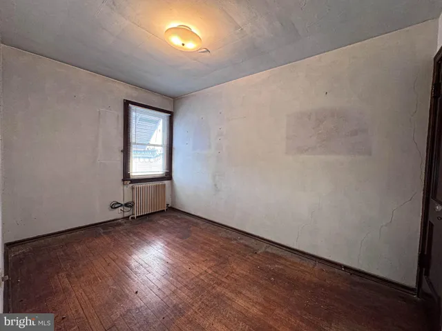 a view of an empty room with wooden floor and closet