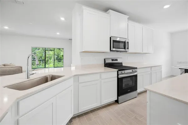 a living room with stainless steel appliances furniture and a kitchen view