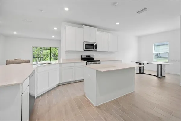 a large kitchen with a refrigerator a sink and cabinets