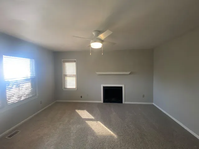 an empty room with a fireplace and windows