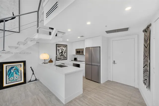 a kitchen with stainless steel appliances a refrigerator a sink dishwasher a oven with white cabinets and wooden floor