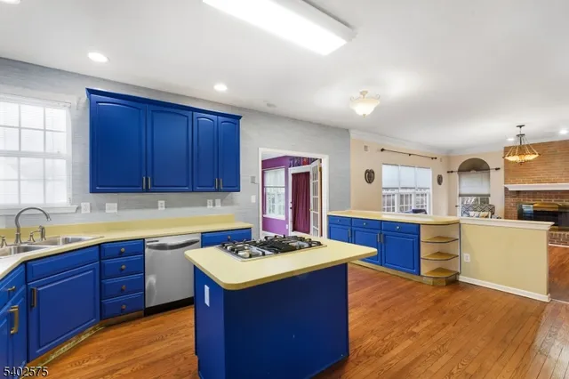 a kitchen with stainless steel appliances granite countertop wooden cabinets a sink dishwasher and a stove with wooden floor