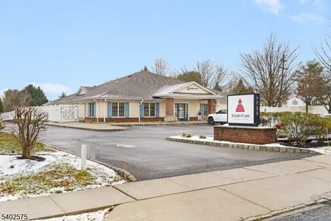 a view of a white house with a swimming pool and lawn chairs under an umbrella