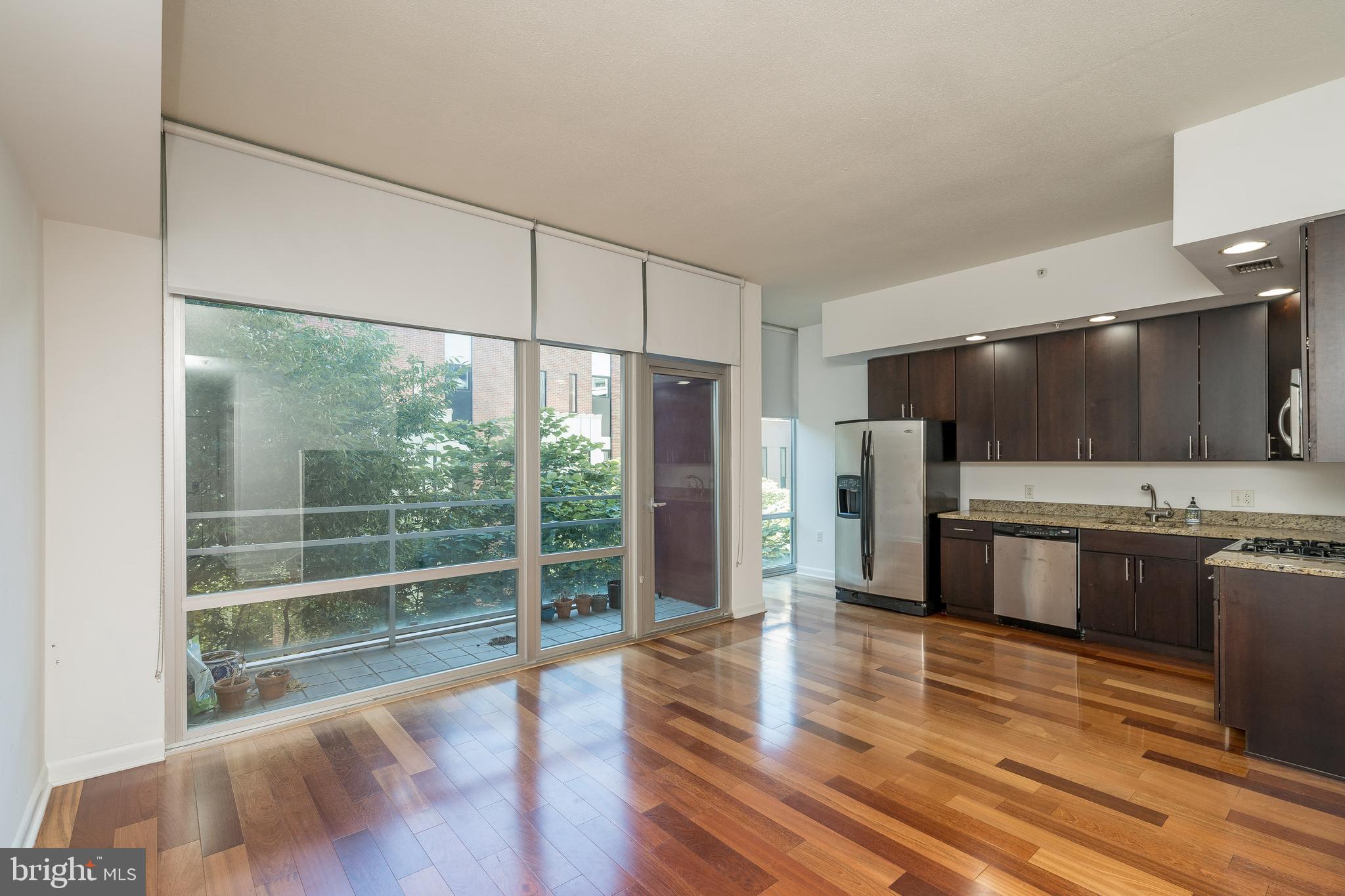 a kitchen with stainless steel appliances wooden floor and a large window