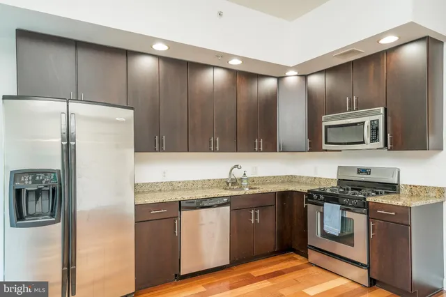 a kitchen with stainless steel appliances granite countertop a refrigerator a stove top oven a sink and dishwasher